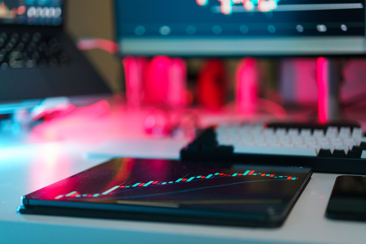 Configuration de trading high-tech avec graphiques sur des écrans de tablette et d’ordinateur, illustrant l’analyse de données et les tendances financières.